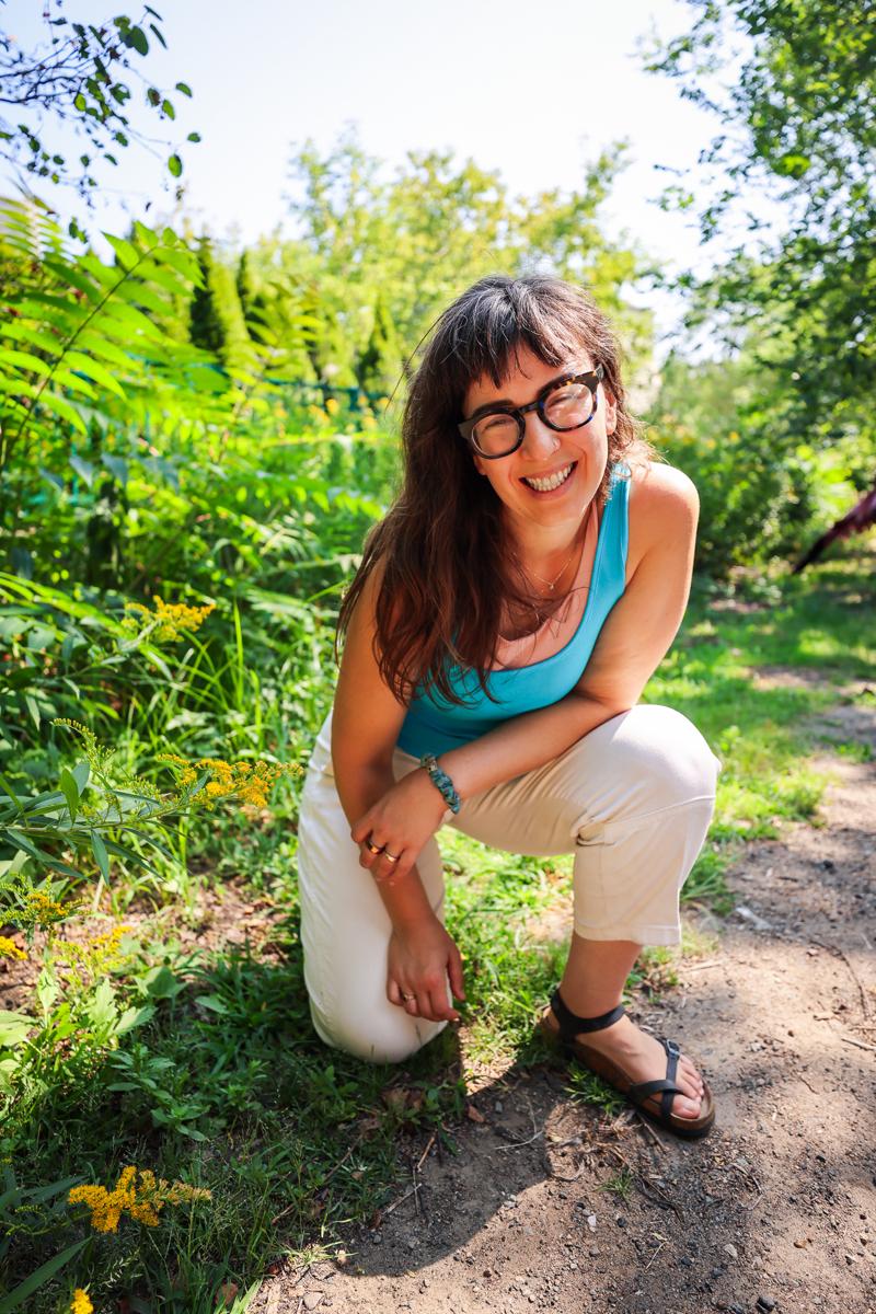 Dr. Cait crouched on a sunny garden path, laughing